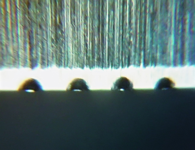 Рисунок 9. Лезвие под микроскопом: сверху видна грубая заточка, формирующая клин лезвия. Светлая полоса - область чистовой заточки с зубчиками, выгнутыми мусатом. Тёмная область внизу - фон.