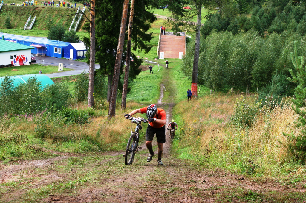 Там, где большинство участников уже идёт пешком, будущий победитель гонки Максим Гоголев (он в глубине кадра) продолжает уверенно двигаться на велосипеде. 