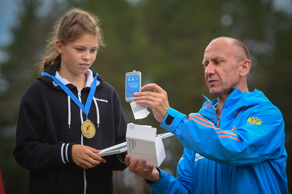 Алексей Нуждов вынимает из коробки и демонстрирует одной из участниц соревнований приз - смартфон Galaxy. 