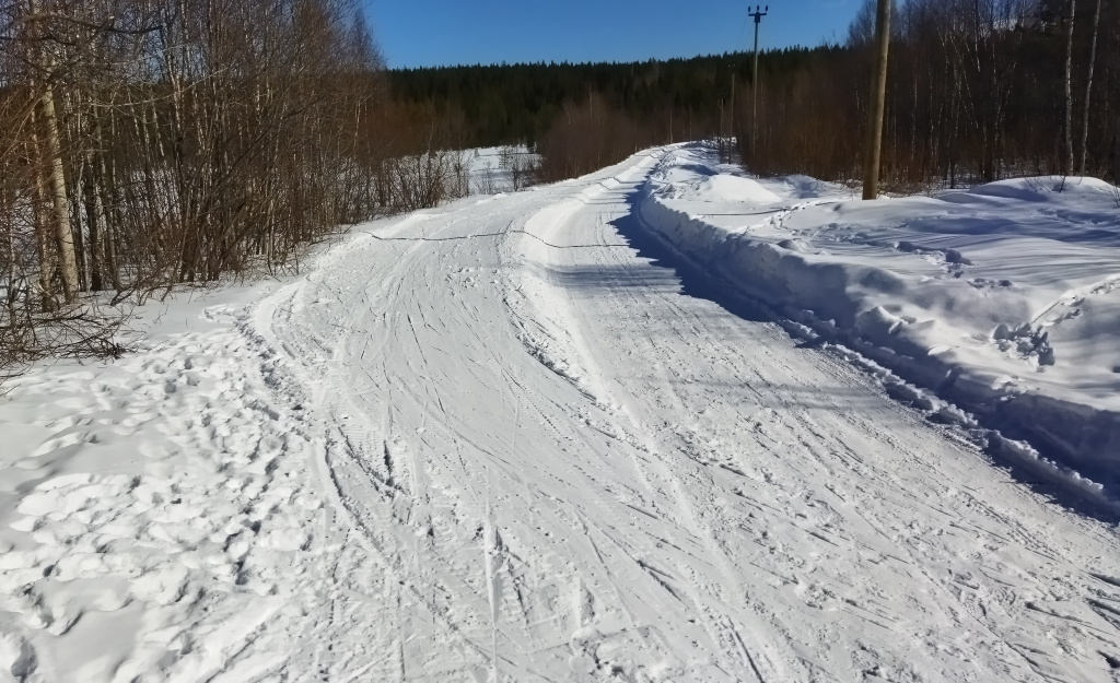 В прошлом году в этом месте марафон пришлось пустить прямо по этой дороге, идущей к Тетюшкинским дачам. Но в этом году удалось соорудить рядом с дорогой такую вот полку, на которой в день гонки будет нарезано две лыжни.Это самое проблемное место всей трассы - здесь относительно оживлённый (по меркам Кандалакши) автомобильный трафик и здесь постоянно ездят снегоходы, не желающие придерживаться своего коридора и норовящие раз за разом заехать на лыжню. После гонки 2024 года Андрей Тютерев сказал, что они постараются в будущем найти какое-то решение и попытаются увести гонку в сторону от этой дороги.